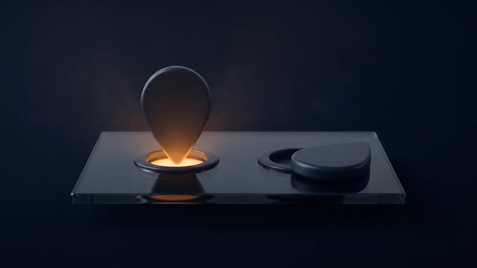 A broad flat base plate of dark smoked glass resting in a deep blue void, holding two identical smooth teardrop location markers, the left one standing upright seated deep in a socket with warm amber light welling out around its foot, the right one lying flat and dark beside its own empty socket