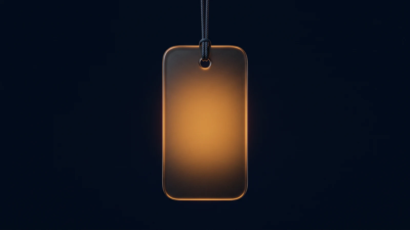 A single blank label tag of dark smoked glass hanging face-on from a fine dark cord in a deep blue void, lit from within by warm amber, a small round hole near its top edge
