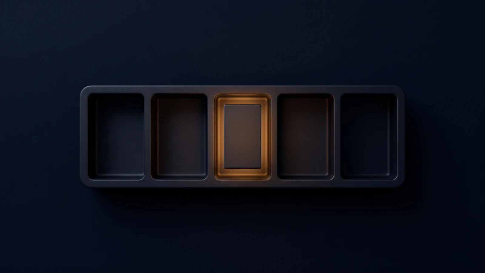 A broad shallow fitted tray of dark matte glass seen from directly above in a deep blue void, cut into five identical upright rectangular bays, four empty and dark and the center bay holding one blank block washed warm amber from inside the bay